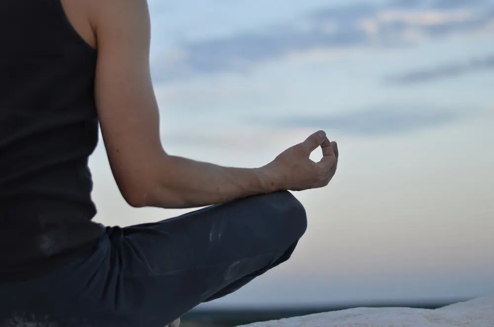 a person meditating on a rock