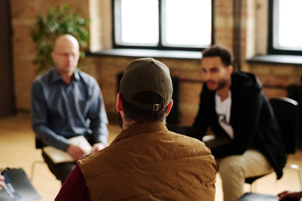 Rear view of one of attendants of mental support group for those with post traumatic syndrome sitting in front of psychologist