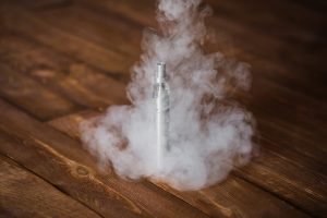 Electronic cigarette on a wooden table. Smoke.