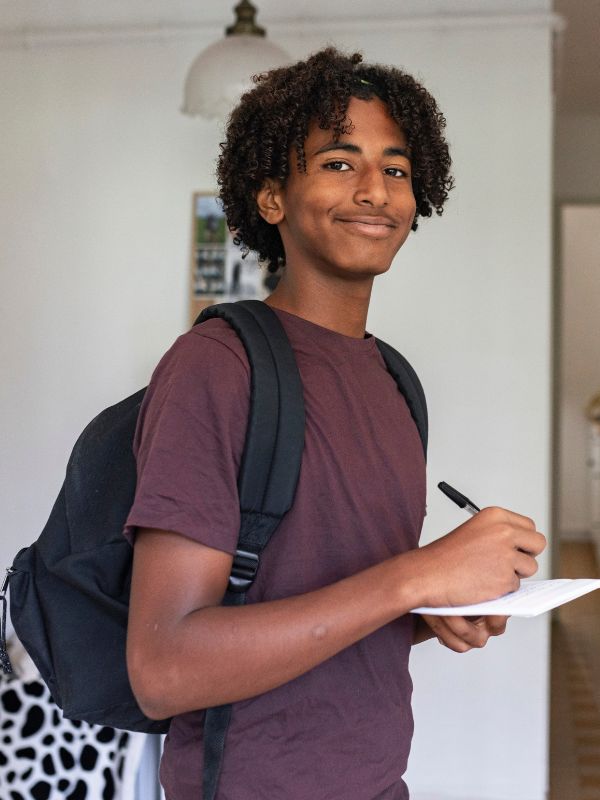 Teen boy with backpack holding a pen and paper